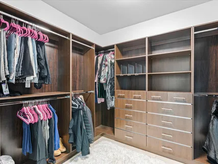 a view of walk in closet with clothes and shoes