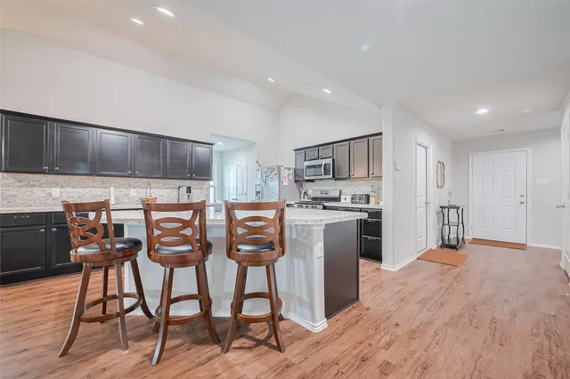 a kitchen with stainless steel appliances kitchen island granite countertop a refrigerator and cabinets