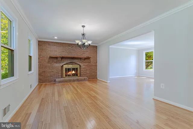 a view of an empty room with wooden floor fireplace and a window