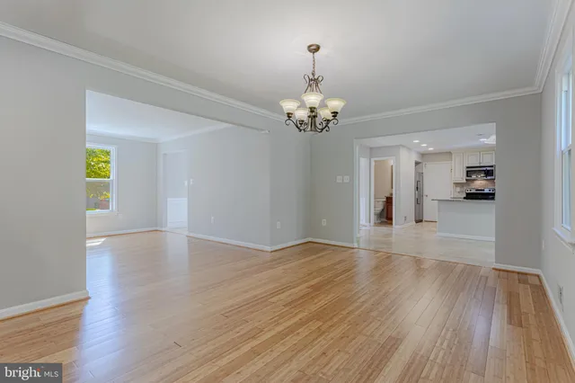 a view of empty room with wooden floor and kitchen view