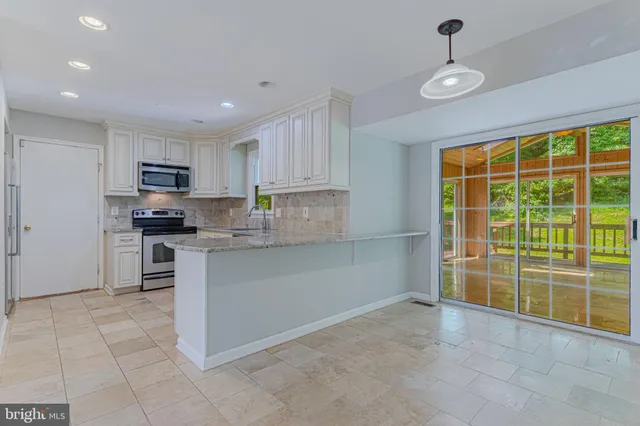 a kitchen with stainless steel appliances granite countertop a stove top oven a sink a counter space and cabinets