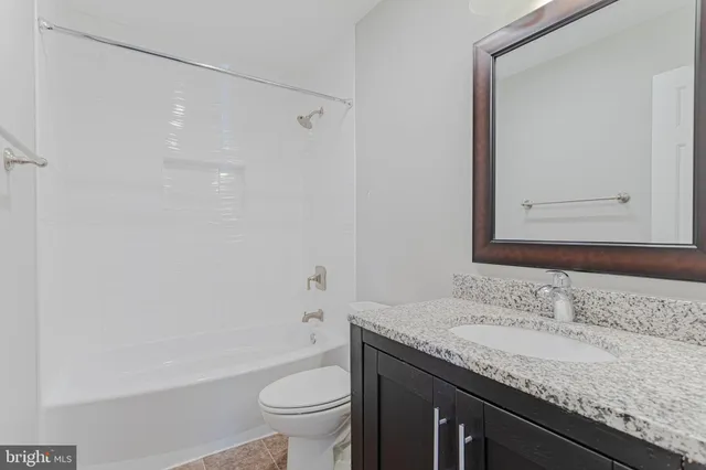 a bathroom with a granite countertop sink a toilet and shower