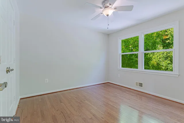 a view of an empty room with a window and wooden floor