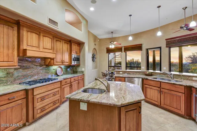 a kitchen with stainless steel appliances granite countertop a sink a stove and a wooden cabinets