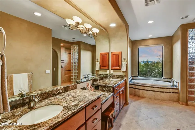 a bathroom with a granite countertop sink a large mirror and a bathtub next to a window