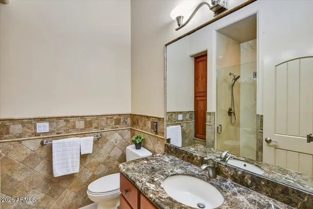 a bathroom with a granite countertop sink mirror vanity and toilet