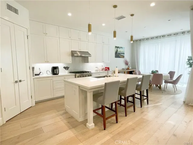 a kitchen with stainless steel appliances kitchen island granite countertop a stove a sink a dining table and chairs