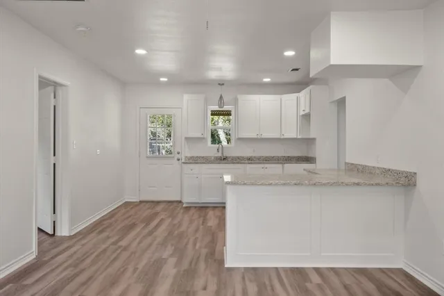 a kitchen with granite countertop a sink cabinets and wooden floor