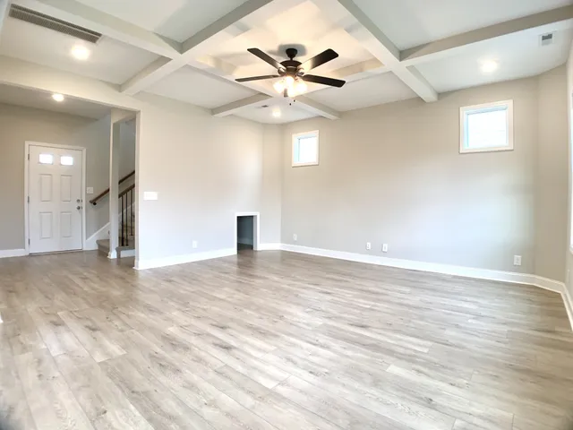 an empty space with wooden floor and a ceiling fan