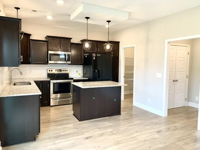 a kitchen with kitchen island stainless steel appliances a sink cabinets and wooden floor