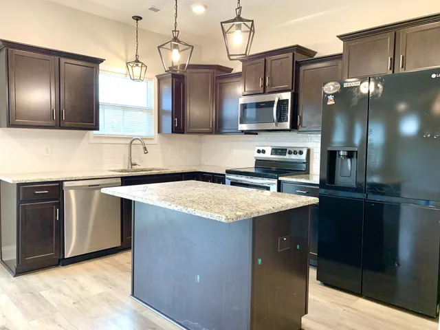 a kitchen with stainless steel appliances granite countertop a sink a microwave and wooden cabinets