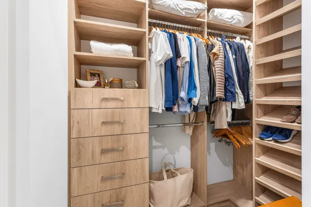 a view of walk in closet with clothes and shoes