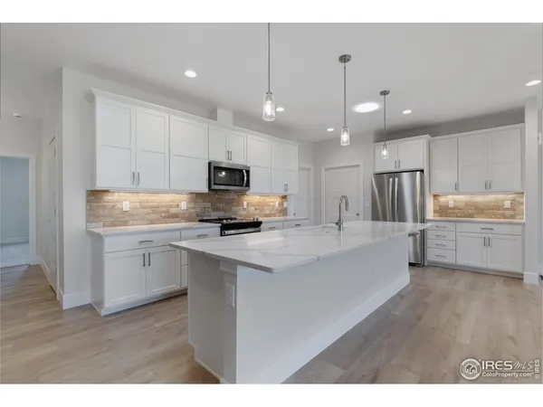 a large kitchen with stainless steel appliances kitchen island a large counter top and a wooden floors