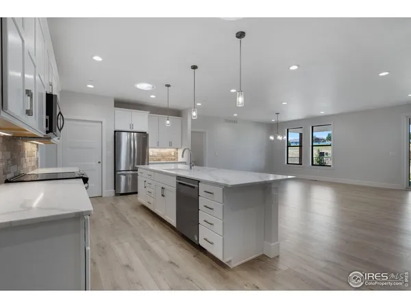 a view of kitchen with kitchen island stainless steel appliances cabinets a sink and a counter top