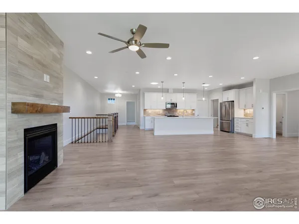 a view of an empty room with wooden floor and a kitchen