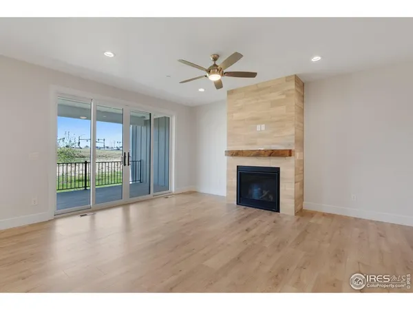 a view of an empty room with wooden floor and a fireplace