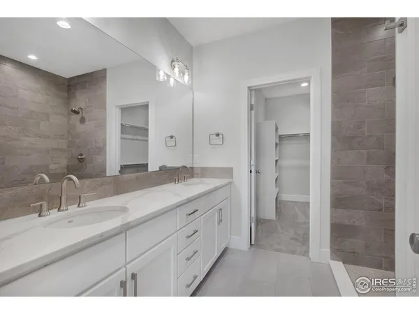 a spacious bathroom with a granite countertop sink a mirror and a shower