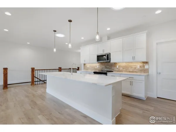a view of a kitchen with kitchen island a counter top space appliances and a ceiling fan