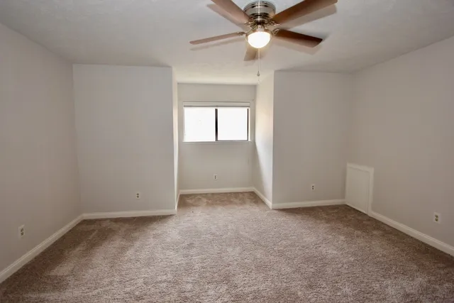 an empty room with ceiling fan and windows