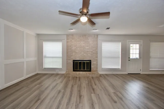 a view of an empty room with wooden floor and a fireplace