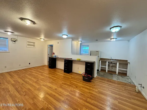 a view of a kitchen with kitchen island a sink wooden floor and a large window