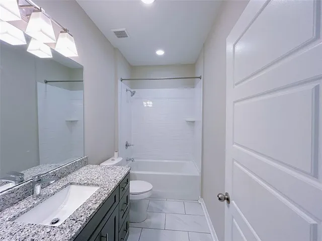 a bathroom with a granite countertop sink a toilet and shower