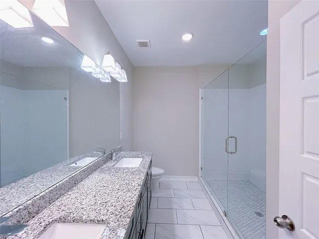 a bathroom with a granite countertop sink a toilet and shower