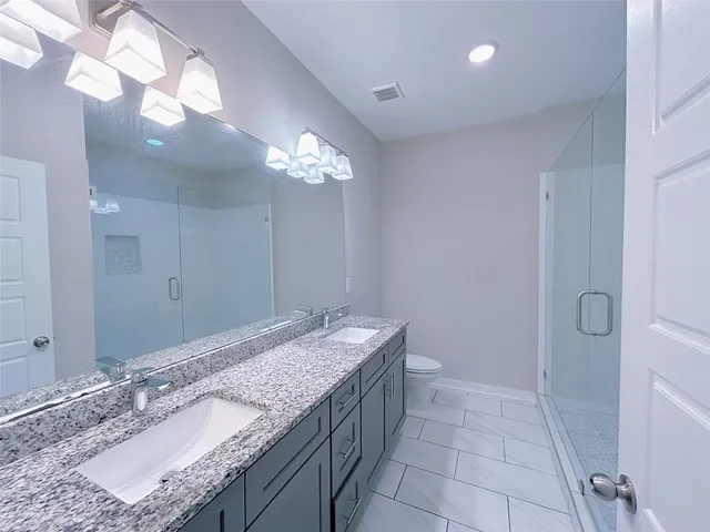 a bathroom with a granite countertop sink a toilet and a mirror