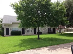 a front view of a house with a garden and trees