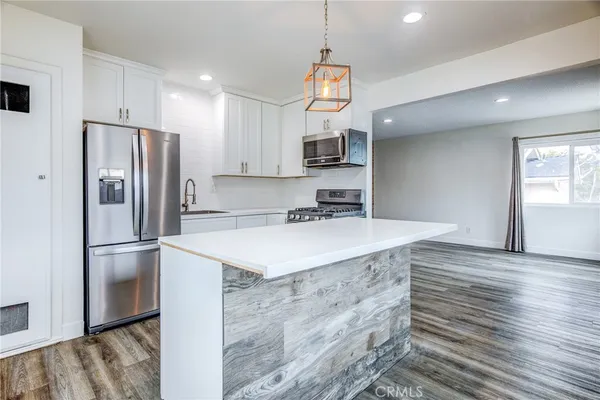 a kitchen with kitchen island a sink stainless steel appliances and refrigerator