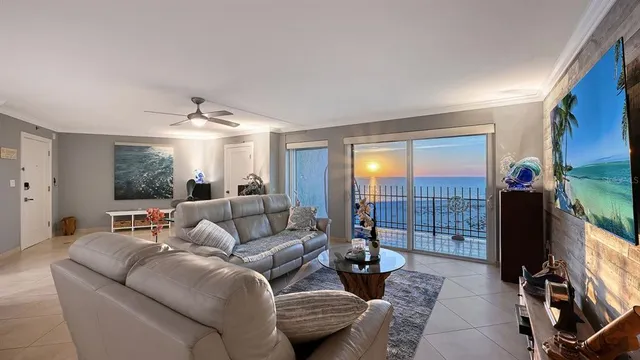 a living room with furniture a flat screen tv and a floor to ceiling window
