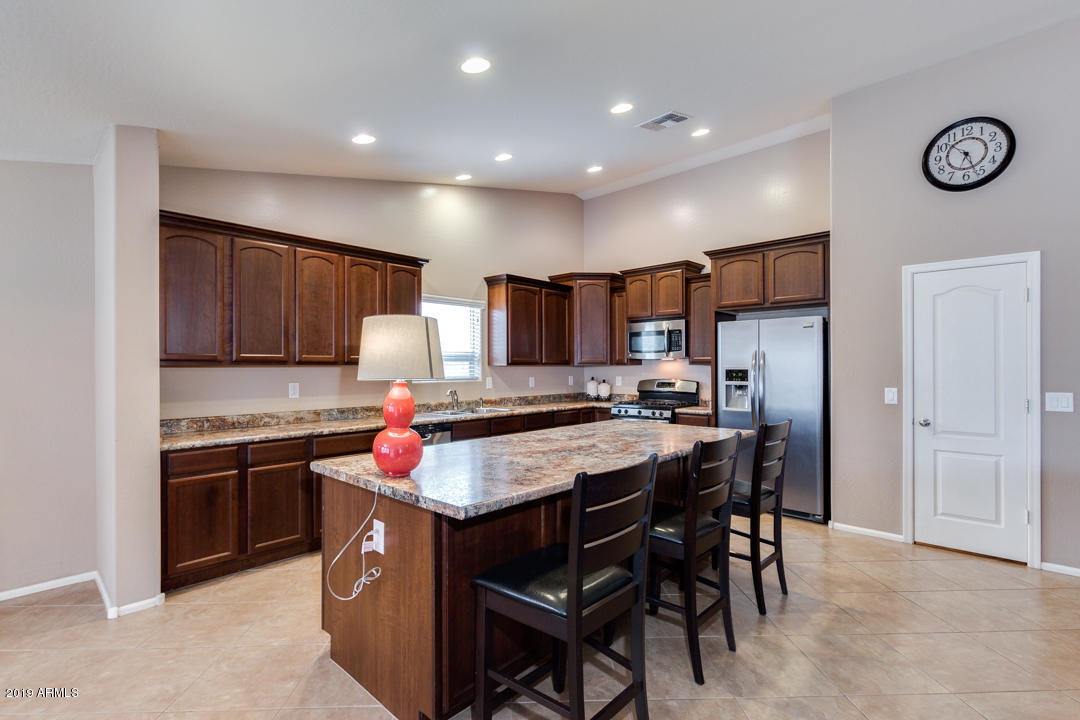 17776 West Charter Oak Road Surprise, AZ 85388 - Photo 12 of 35 a kitchen with stainless steel appliances granite countertop a stove top oven a sink dishwasher and a refrigerator with wooden cabinets