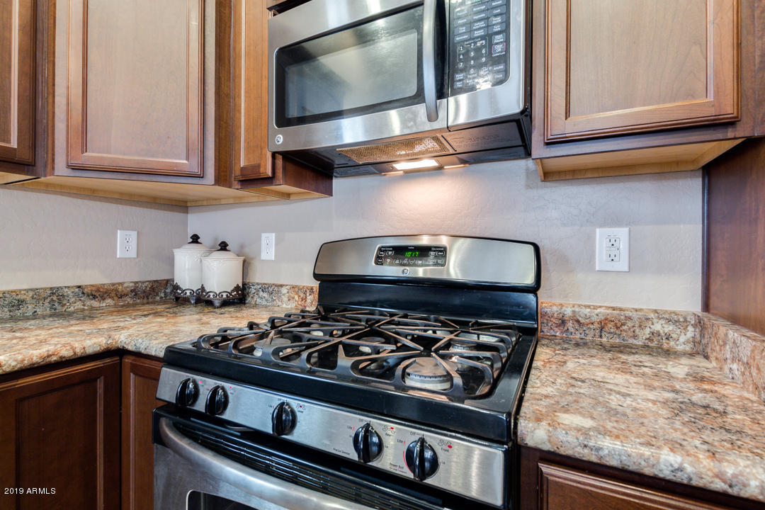 17776 West Charter Oak Road Surprise, AZ 85388 - Photo 13 of 35 a kitchen with stainless steel appliances granite countertop white cabinets and a stove top oven