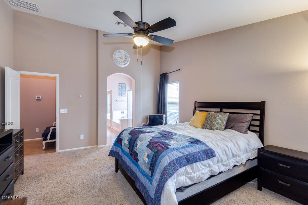 17776 West Charter Oak Road Surprise, AZ 85388 - Photo 18 of 35 a bedroom with a large bed and a chandelier