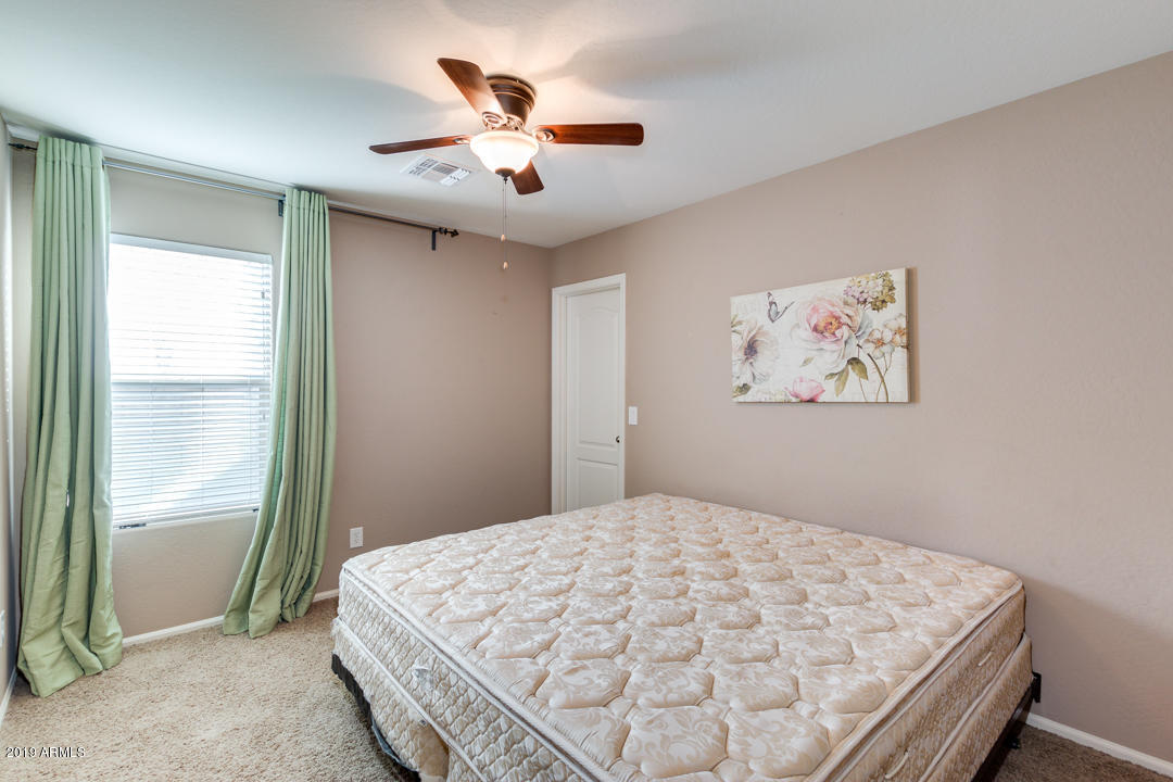 17776 West Charter Oak Road Surprise, AZ 85388 - Photo 25 of 35 a bedroom with a large bed and a chandelier