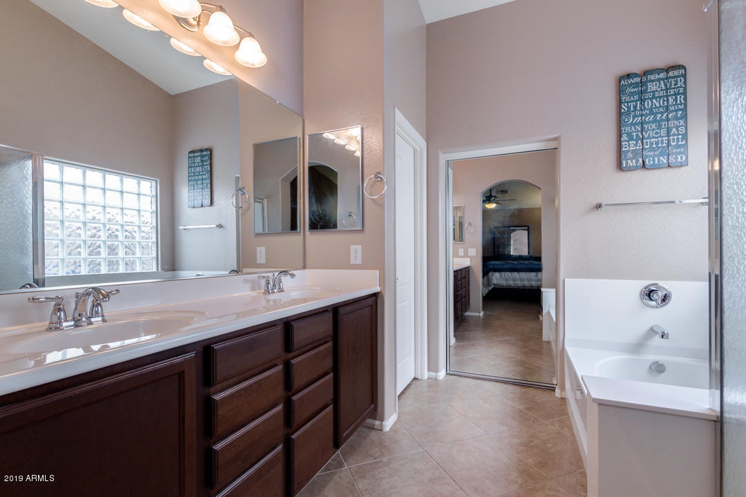 17776 West Charter Oak Road Surprise, AZ 85388 - Photo 35 of 35 a en suite bathroom with a double vanity sink a large mirror and shower