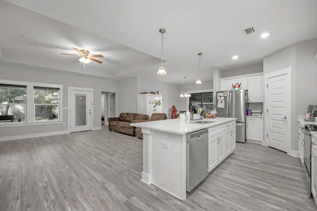 a large kitchen with kitchen island a stove a refrigerator a sink dishwasher with a dining table and chairs with wooden floor