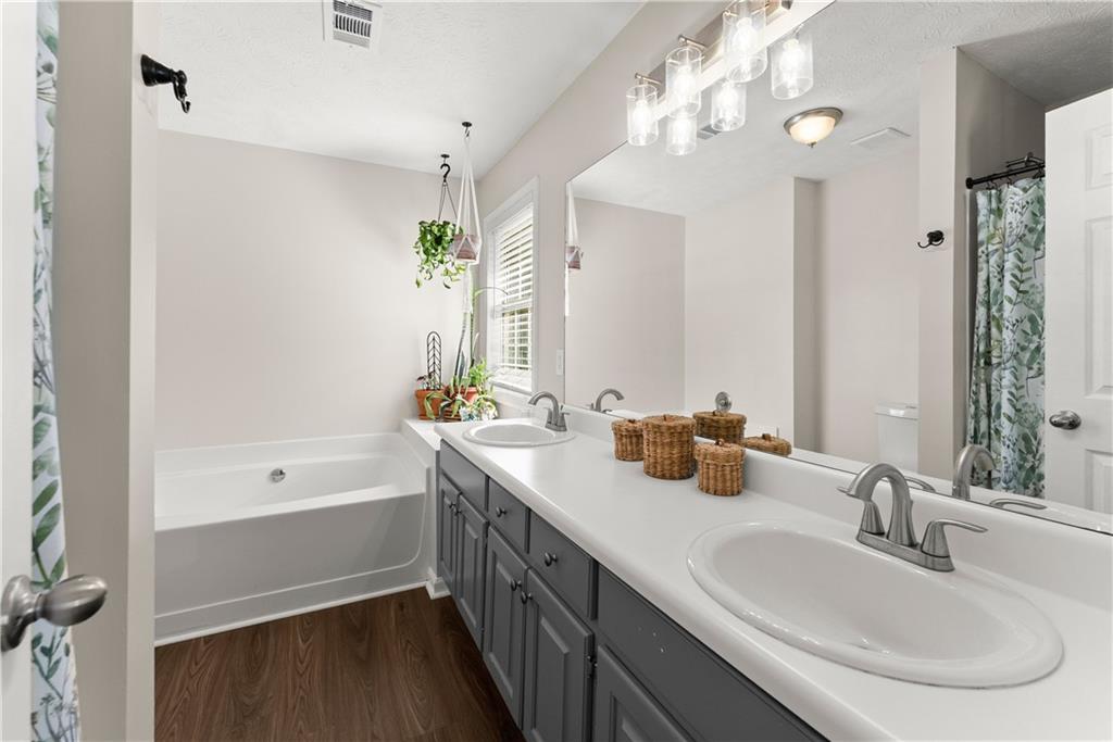 709 Muirfield Drive Winder, GA 30680 - Photo 29 of 65 a bathroom with a double vanity sink a mirror and a bathtub