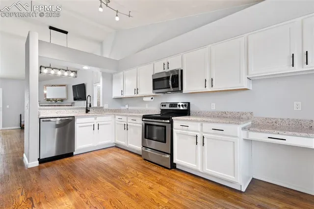 a kitchen with granite countertop white cabinets and stainless steel appliances