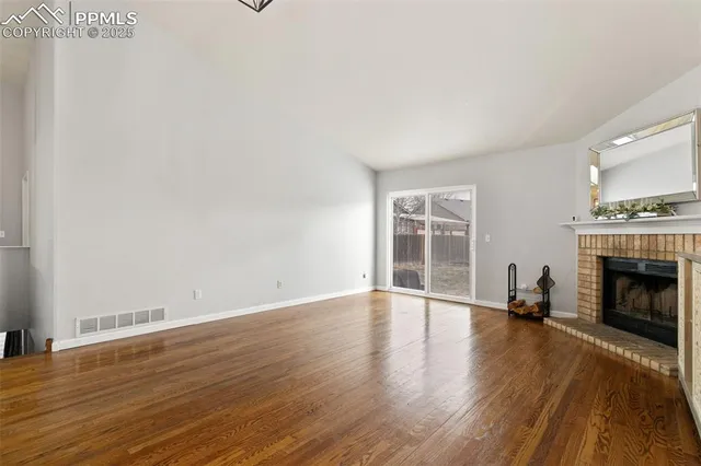 a view of empty room with wooden floor and fireplace