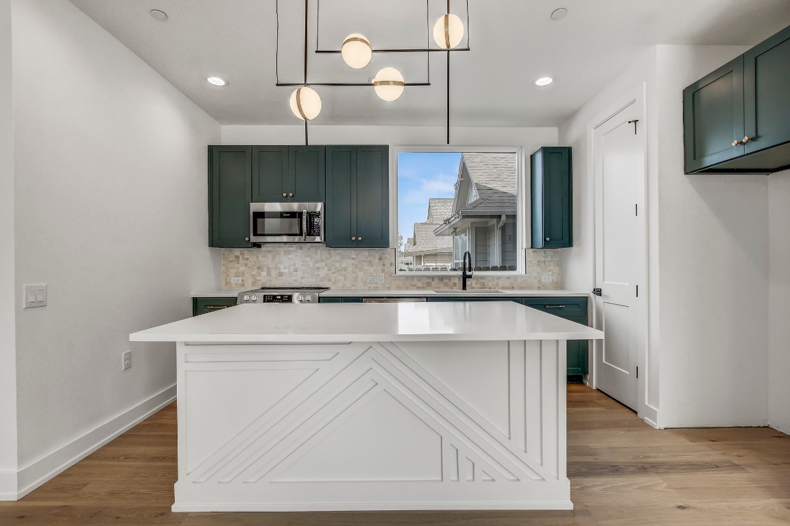 Kitchen with appliances with stainless steel finishes, a sink, decorative backsplash, light countertops, and recessed lighting