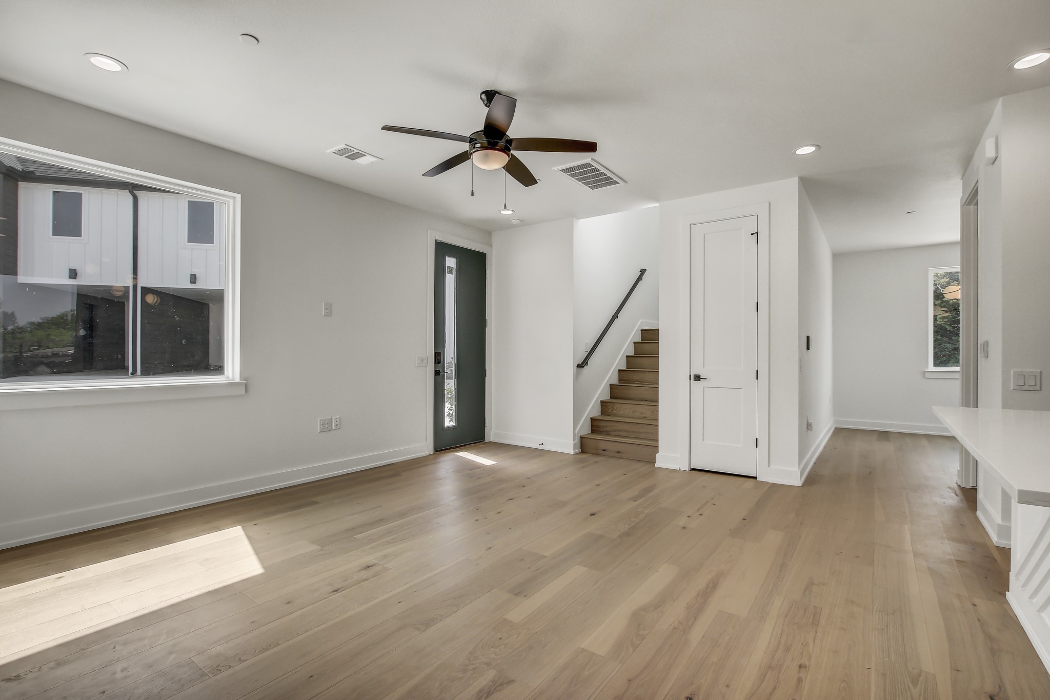 4127 East 12th Street, Unit 1 Austin, TX 78721 - Photo 7 of 30 a view of an empty room with wooden floor staircase and a ceiling fan