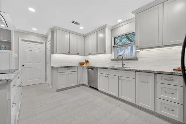 a kitchen with stainless steel appliances granite countertop a sink a stove a refrigerator cabinets and chairs