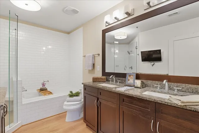 a bathroom with a granite countertop sink a toilet a mirror and bathtub