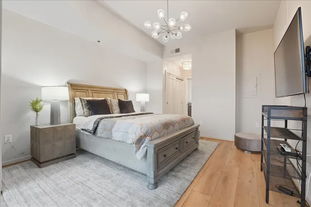 a bedroom with a large bed chandelier and a window