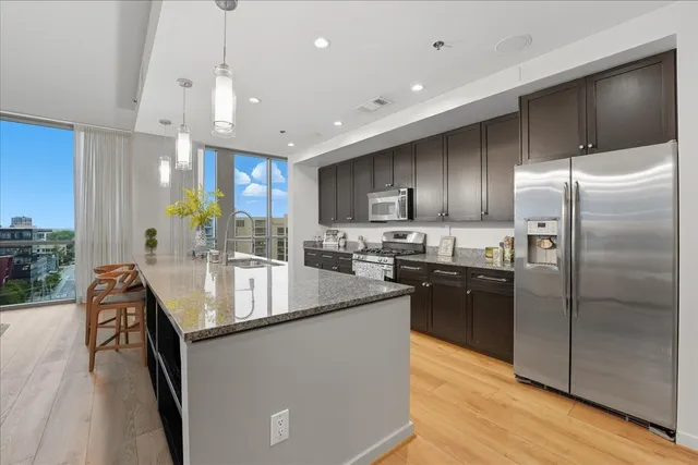 a kitchen with stainless steel appliances granite countertop a sink a stove and a refrigerator