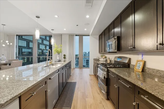 a large kitchen with stainless steel appliances granite countertop plenty wooden cabinets counter space a sink and a stove top oven