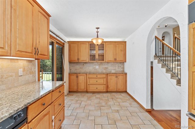 a kitchen with granite countertop a stove a sink and a refrigerator