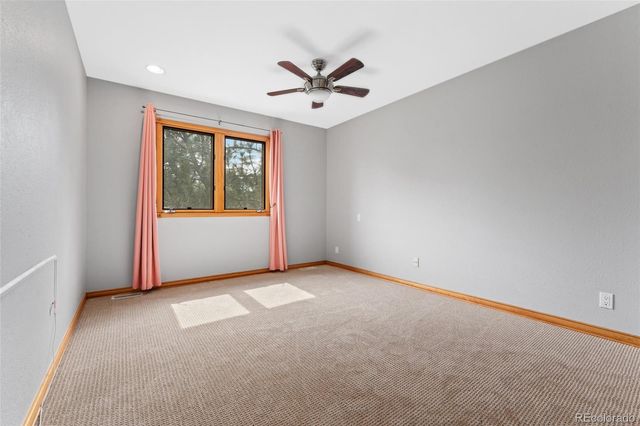 an empty room with a ceiling fan and windows