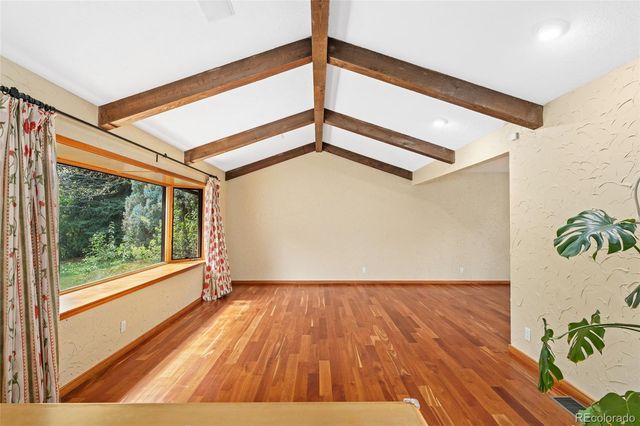 a view of a big room with wooden floor and windows